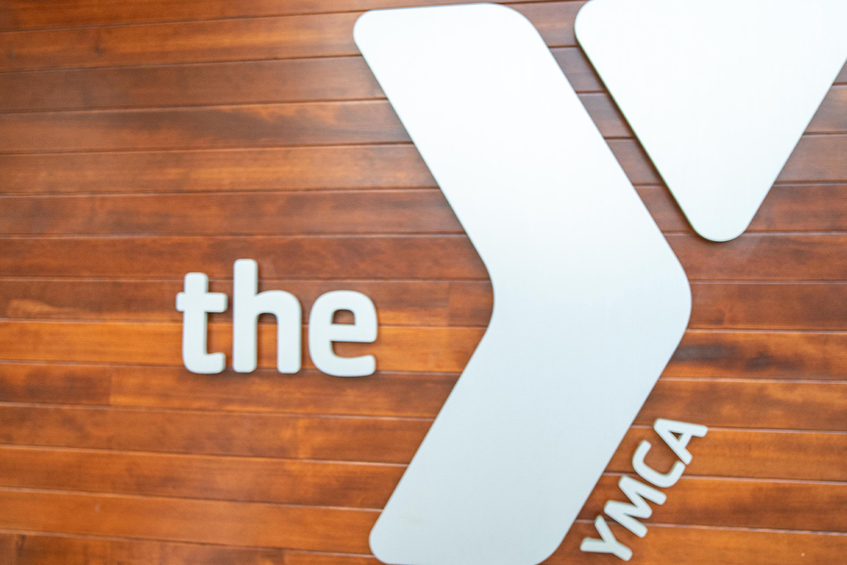 A digital photo of the YMCA logo on a wood paneled wall