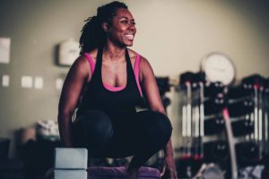 Woman member in black and pink smiles as she holds a sitting pose on top of her mat in her yoga class at the Southwest Family YMCA. 