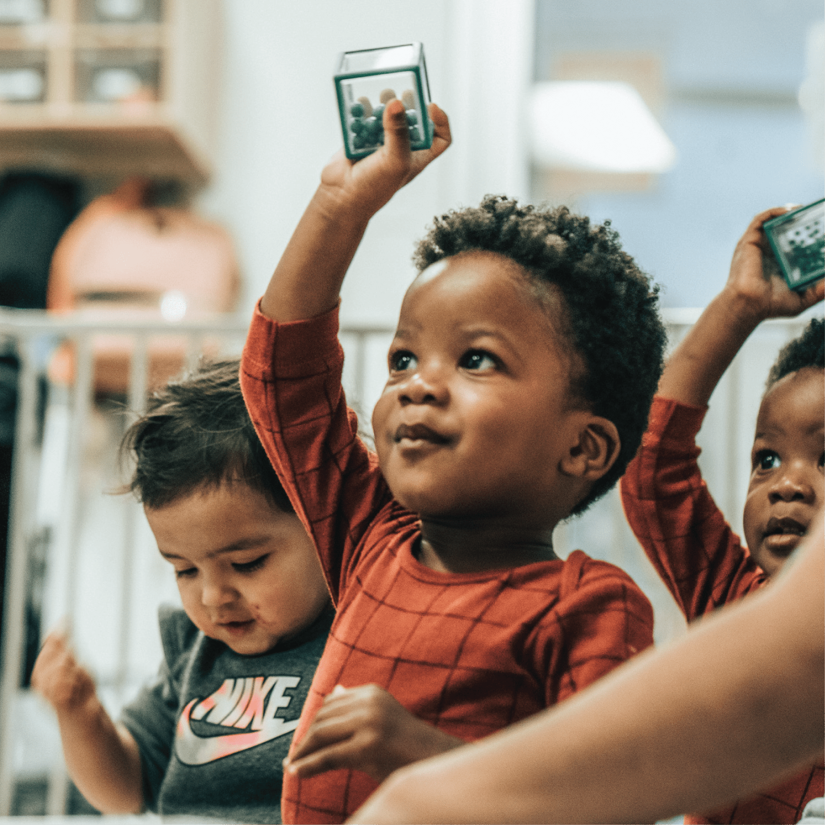 A group of preschoolers hold up cubes with balls inside as part of a gross motor exercise
