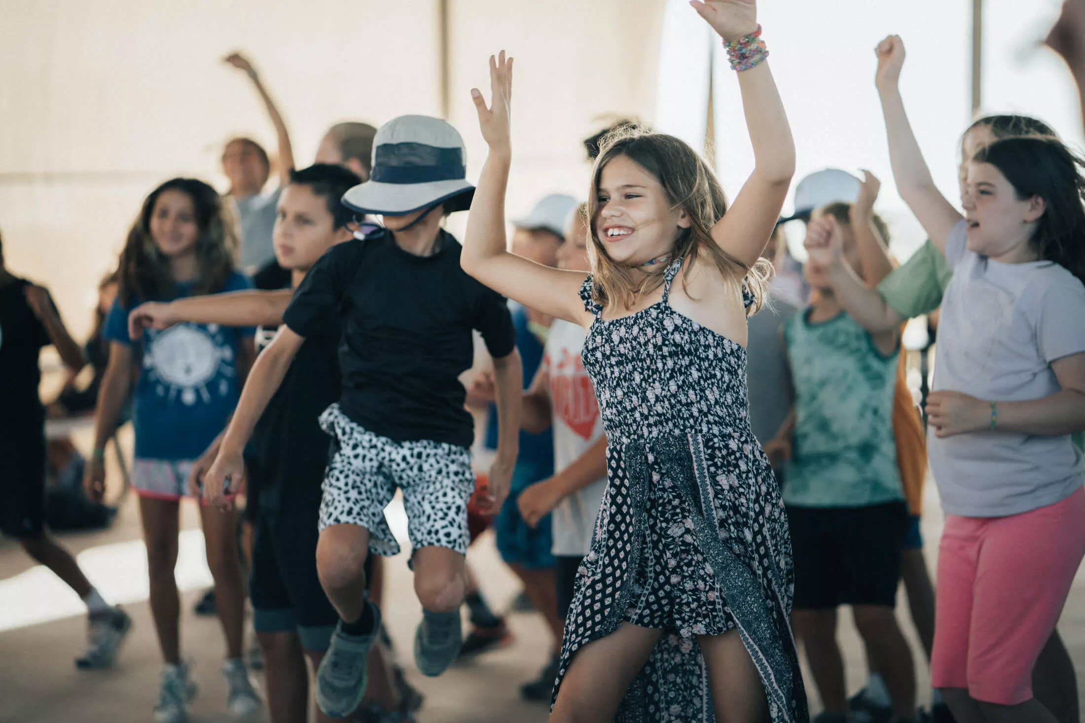 A group of children laugh and smile while dancing.