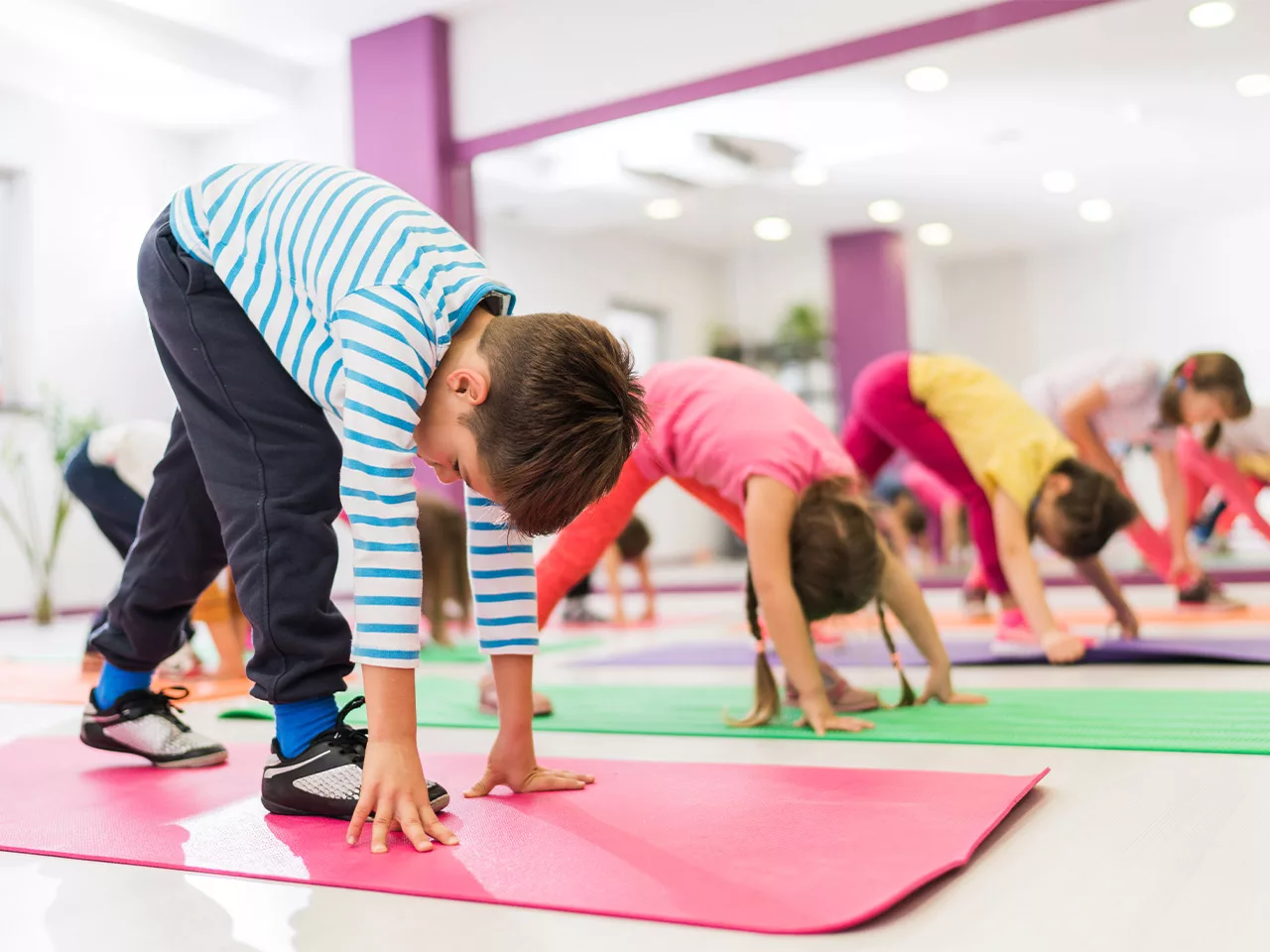 small children on yoga mats bend to touch the floor