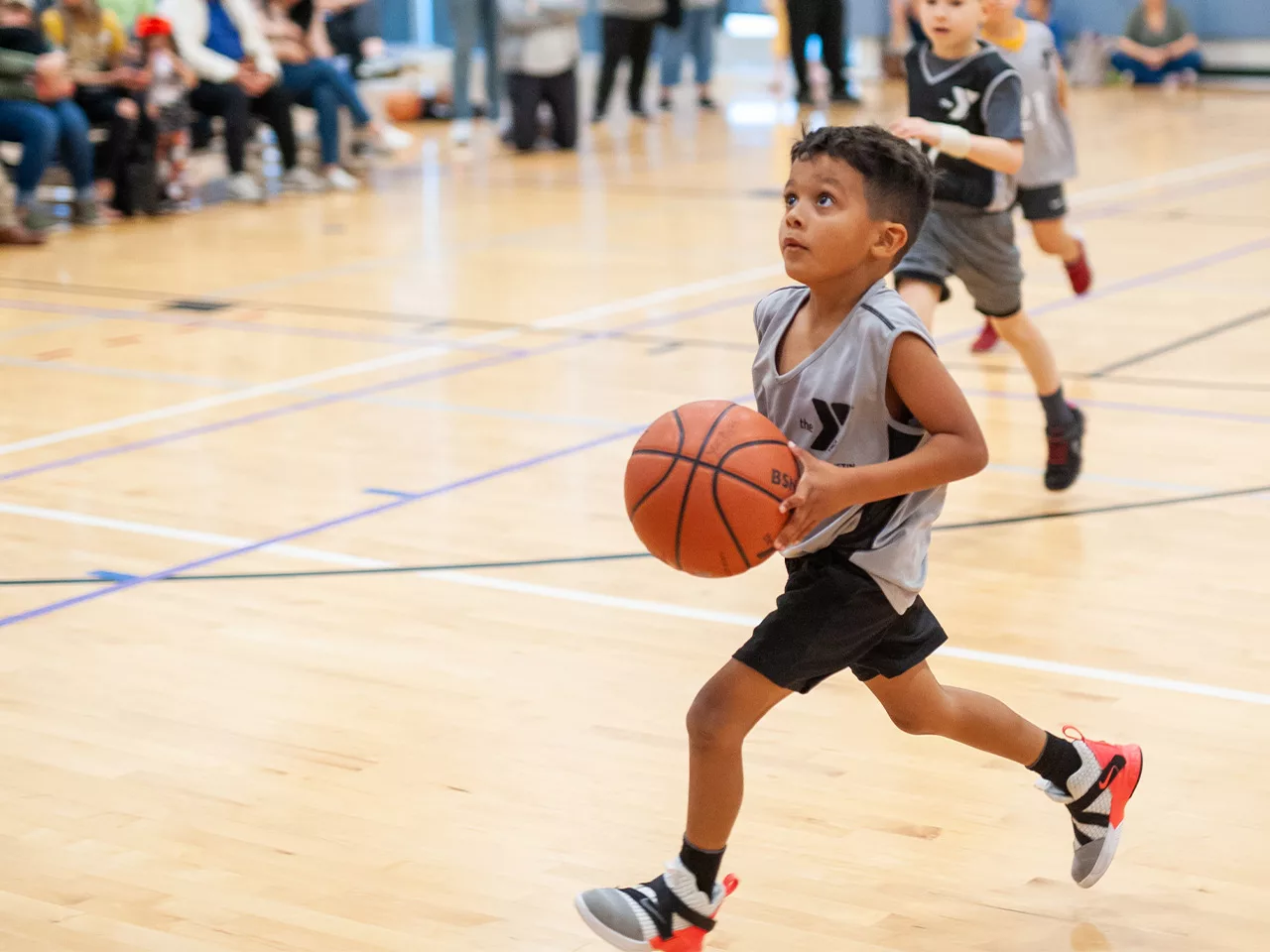A boy holding a basketball runs looking up as if toward a basket.