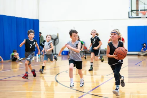 A group of children play basketball. The game looks intense.