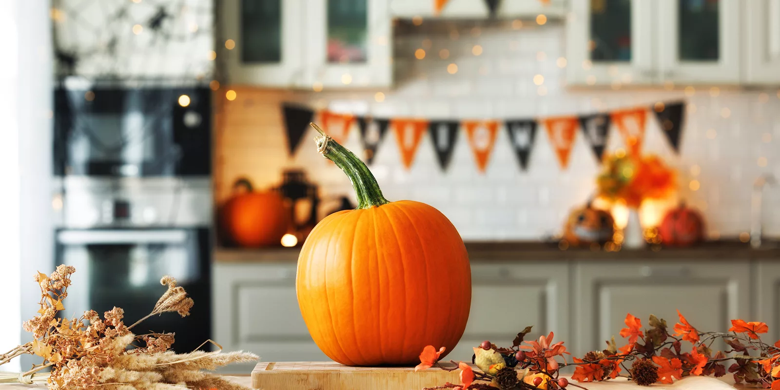A pumpkin sits on a table in a kitchen decorated for Halloween