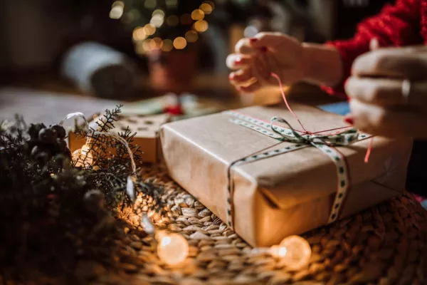 a hand wrapping a holiday gift and tying a bow