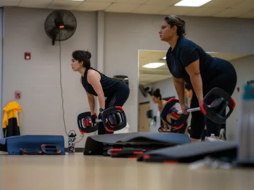 Women participate in an exercise class using barbells.