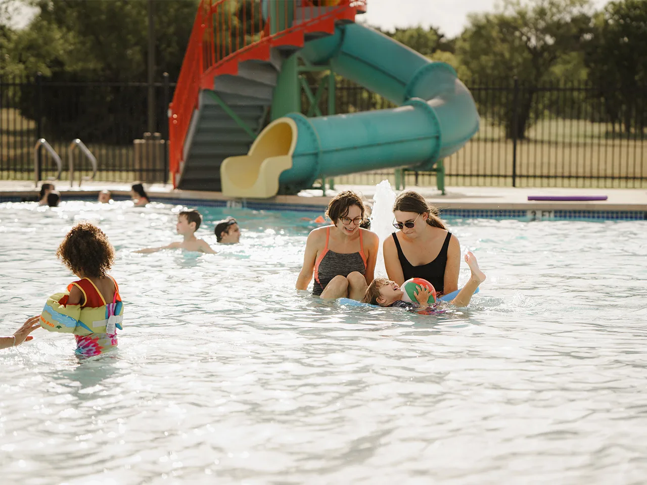 Families play in a sparkling pool.