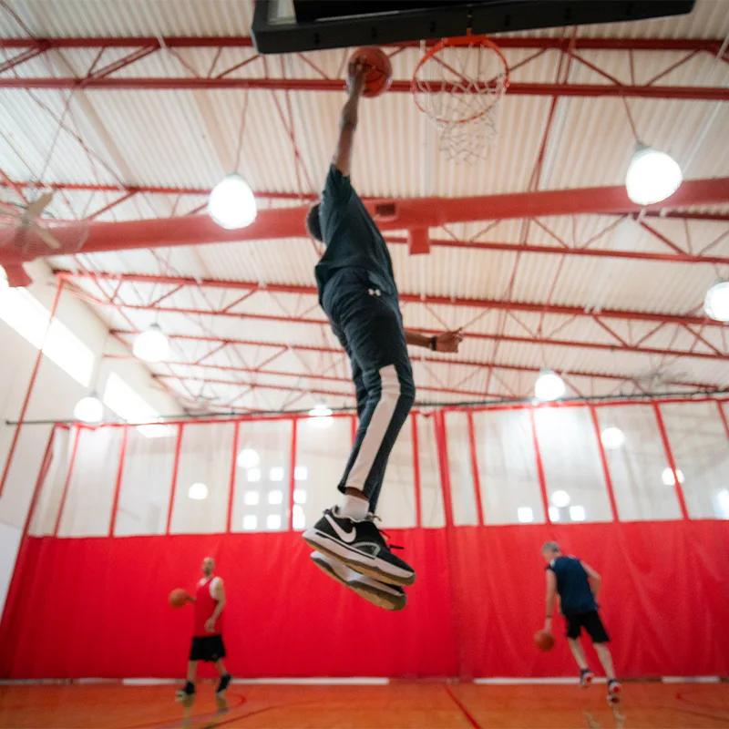 Adults play a game of pickup basketball in a gymnasium.