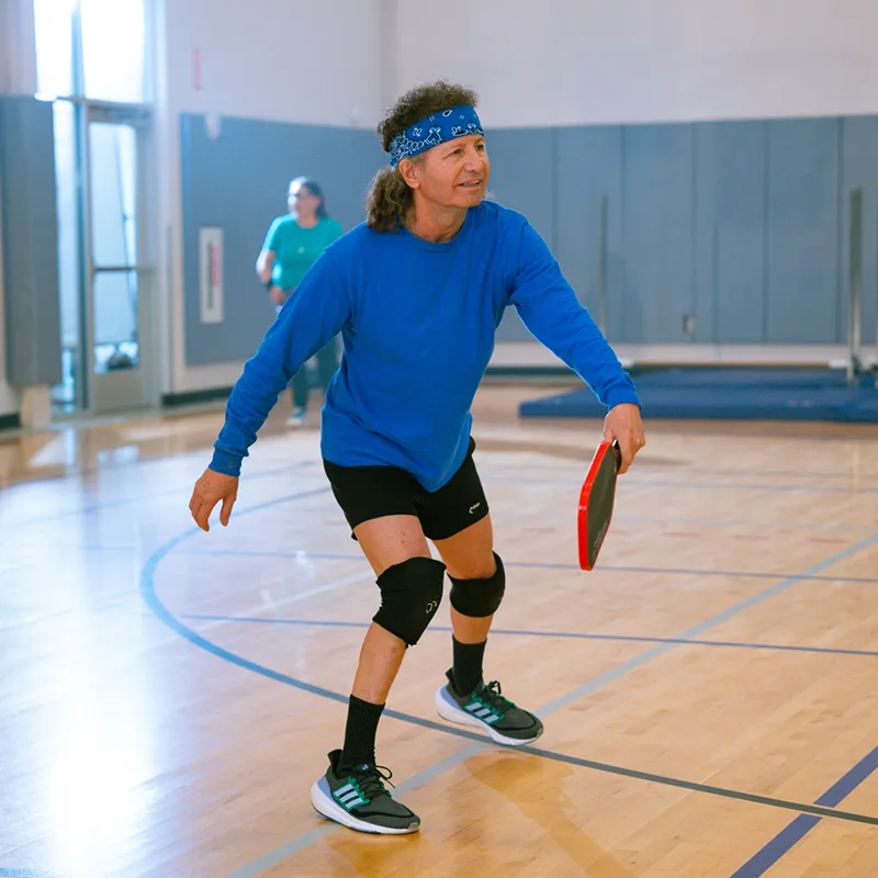 A man plays a game of pickleball in an indoor gymnasium