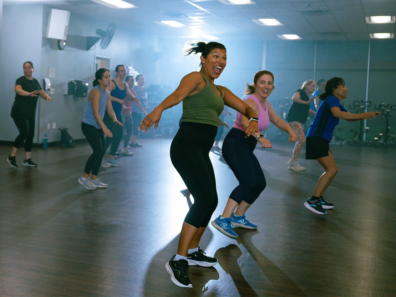 A group of adult women dance joyously in a Zumba class