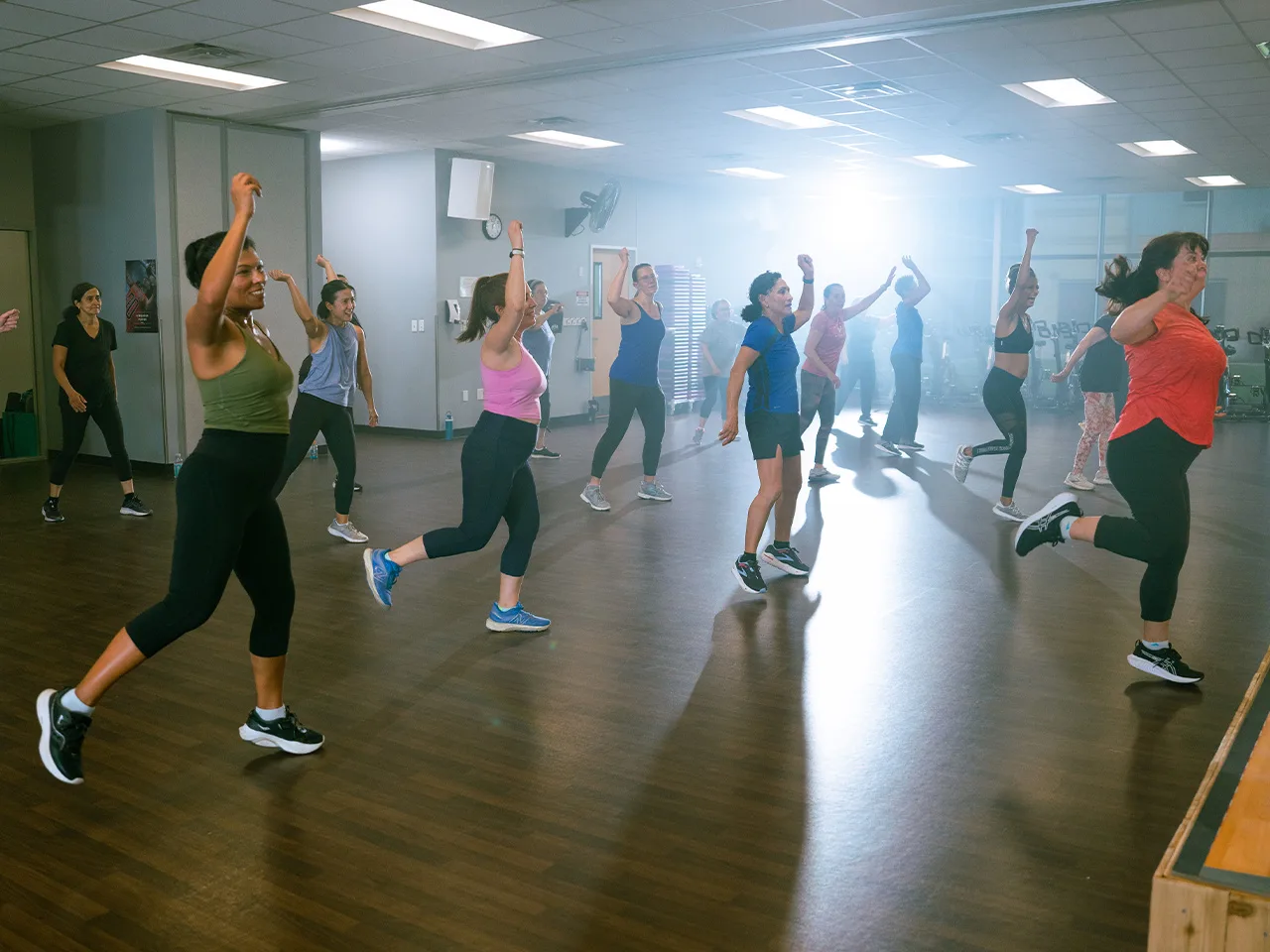 A group of adult women dance joyously in a Zumba class