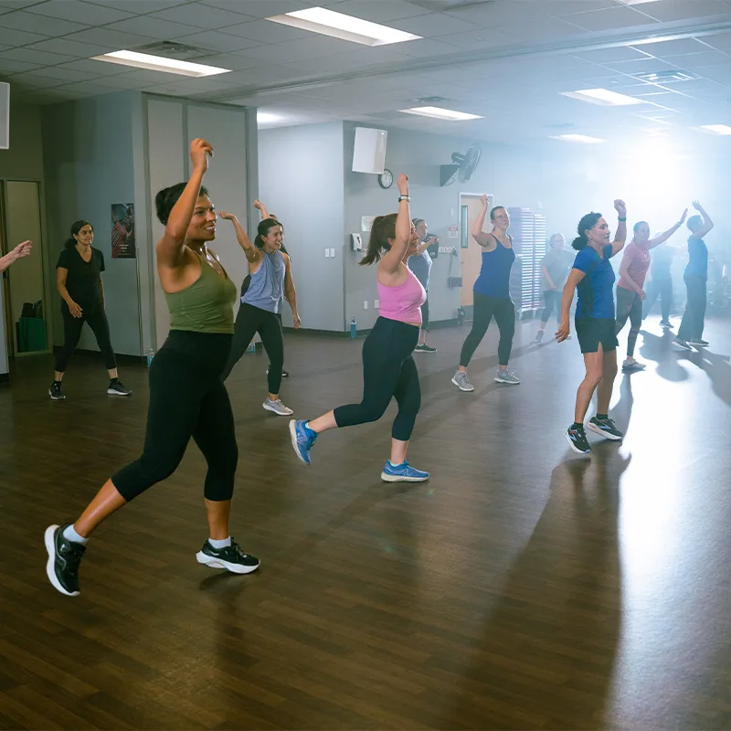 A group of adult women dance joyously in a Zumba class