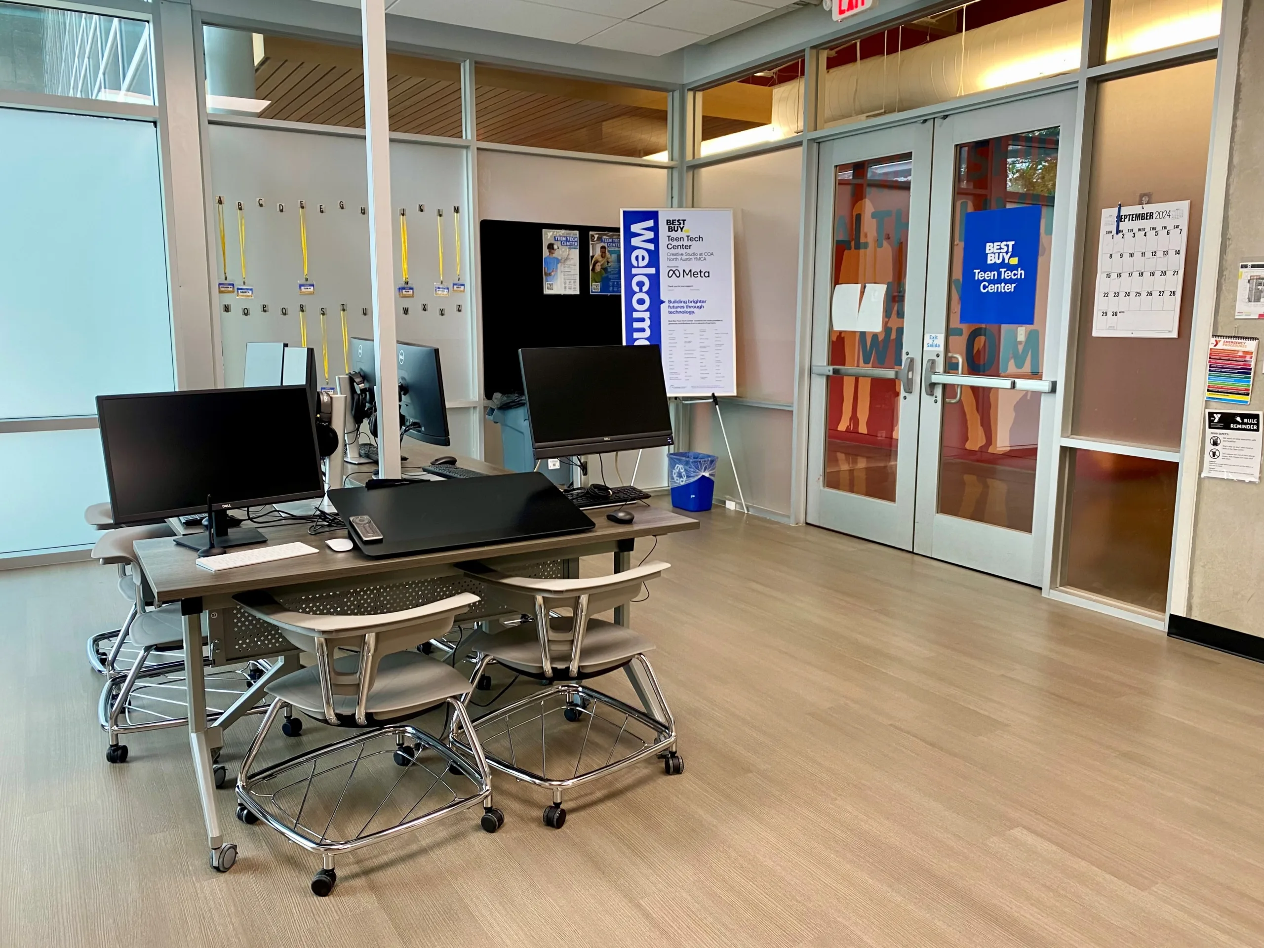 technology equipment is placed on desks in a room with glass walls