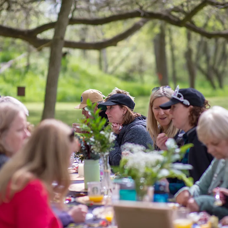 A group of people sit at an outdoor table laid with flowers and festive decorations