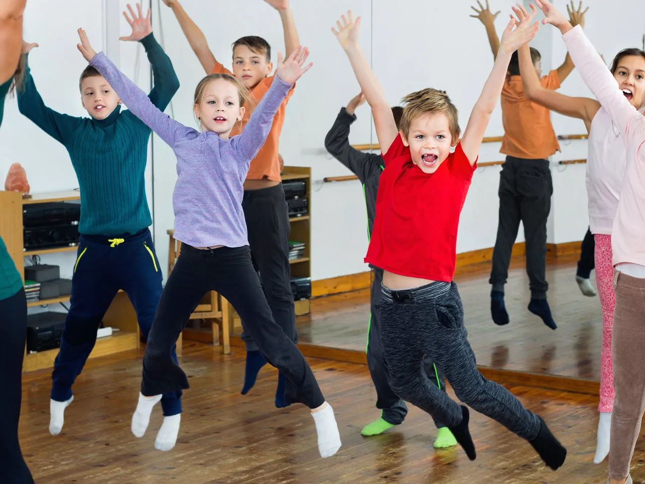 Children in a dance class jump high in the air.