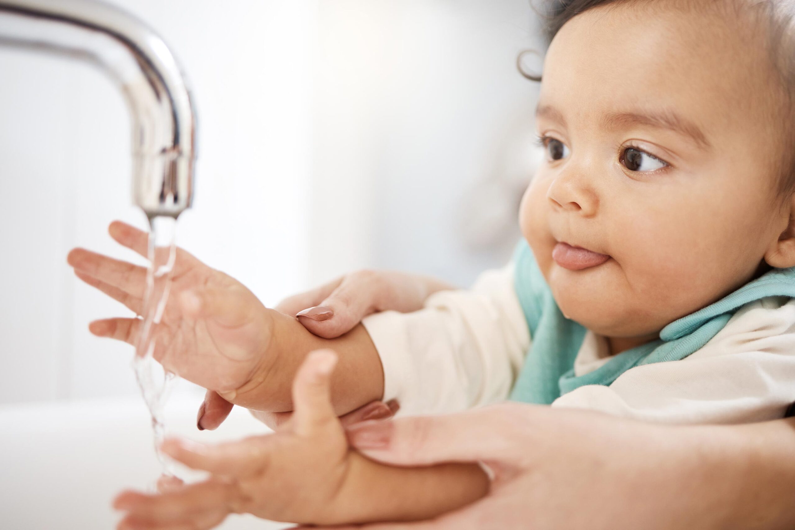 A baby learns how to wash their hands.