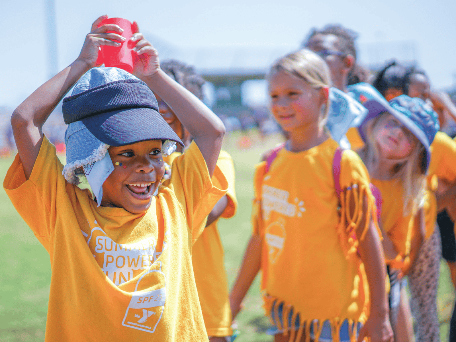 A child smiles broadly as they participate in a water cup relay game on Olympic Day.