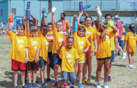 A group of campers raise their water bottles on Olympic Day to practice hydration during the summer heat.